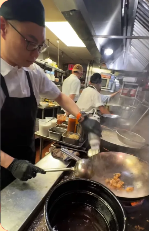 Erik Cheah tossing fried chicken in a wok on the basement line