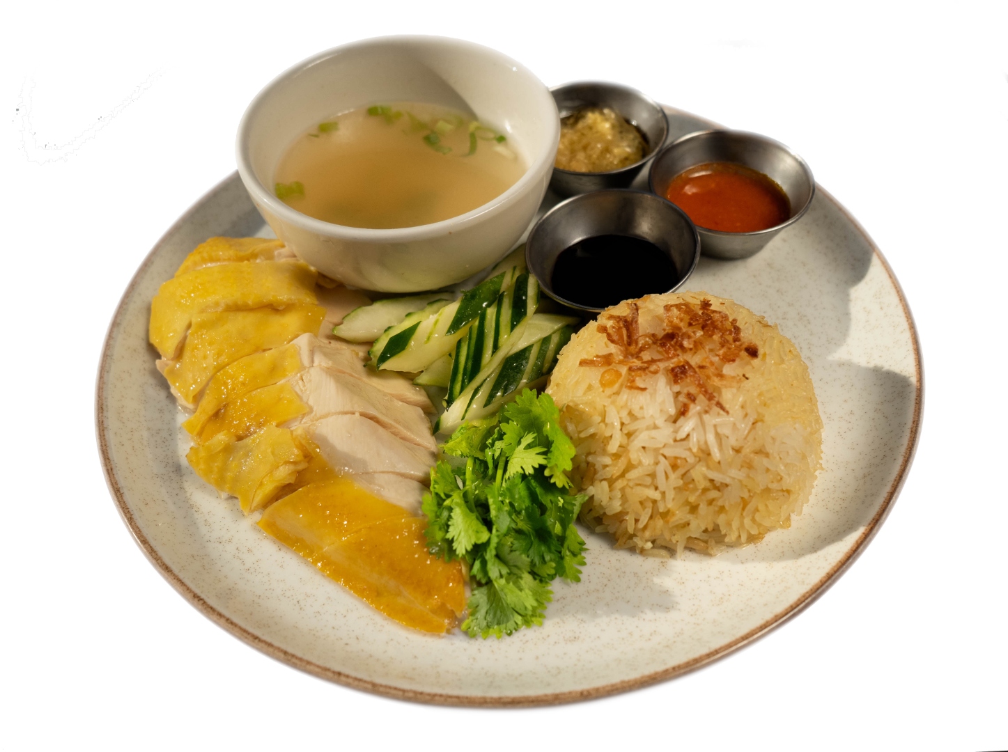 Hainanese chicken over rice with poached chicken, fragrant rice, broth, cucumbers, and house sauces