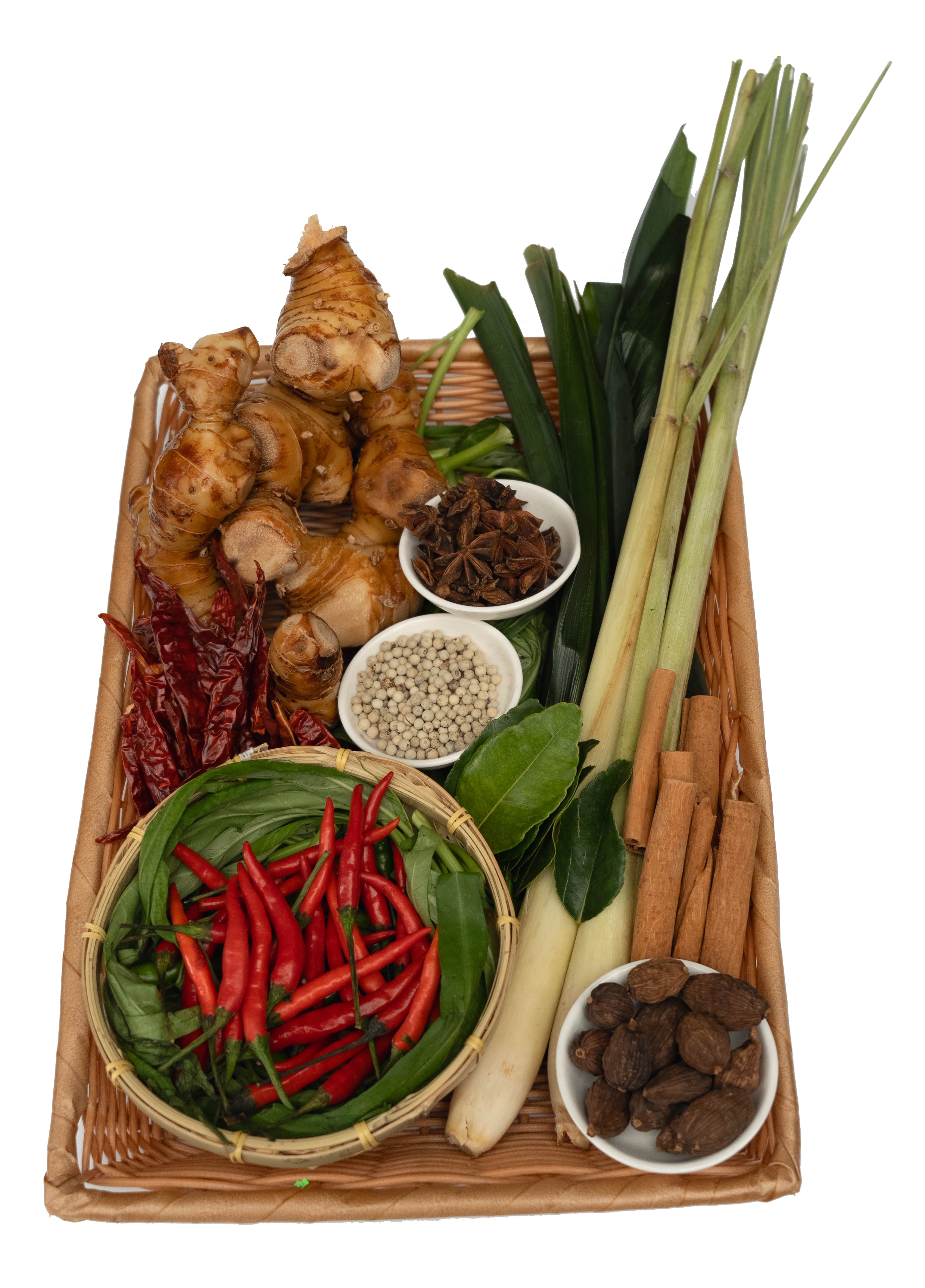 Galangal, lemongrass, pandan, cinnamon, black cardamom and chilies in a market basket